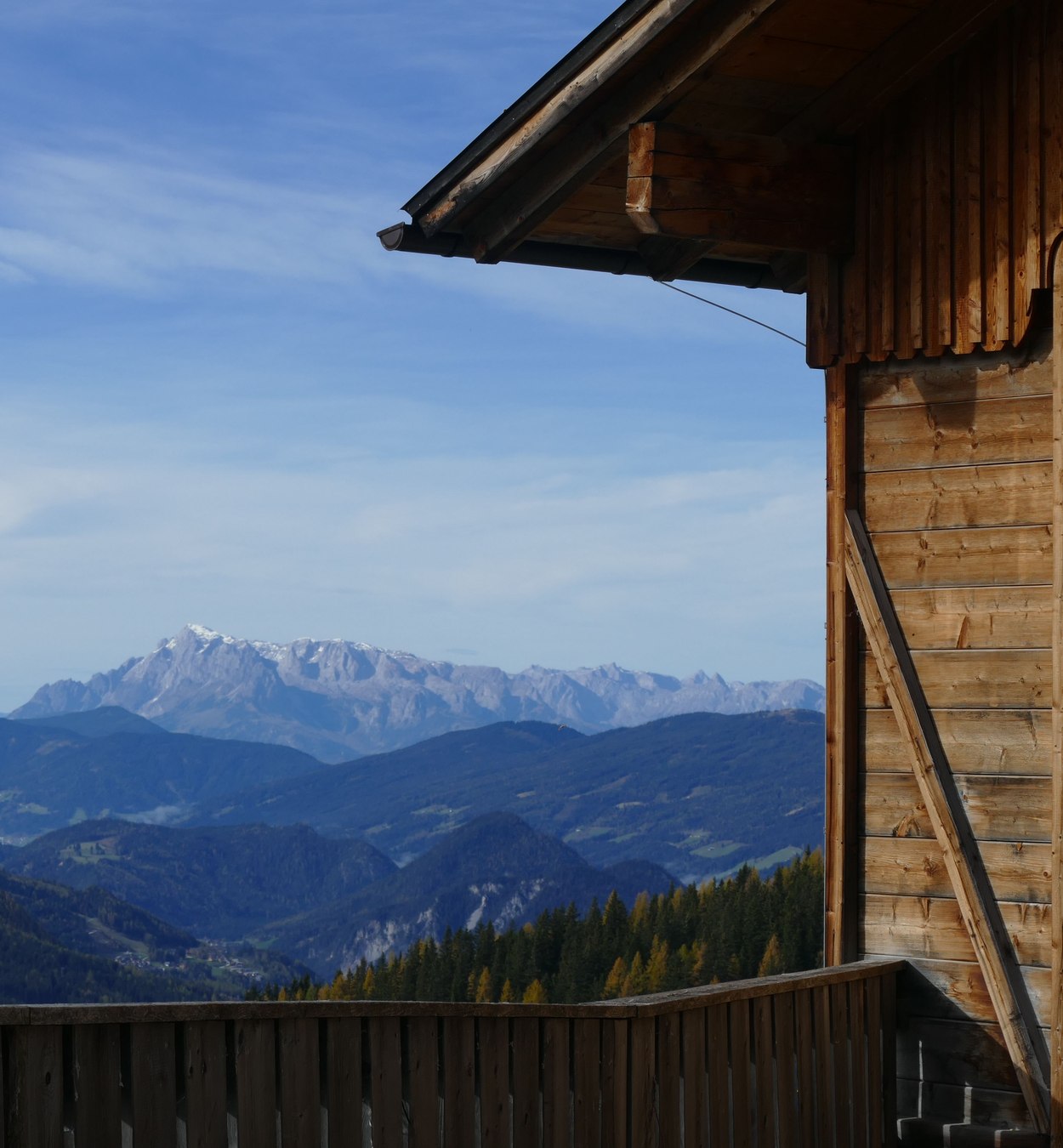 Hölzernes Haus in österreichischer Berglandschaft mit Wiese und weitem Blick